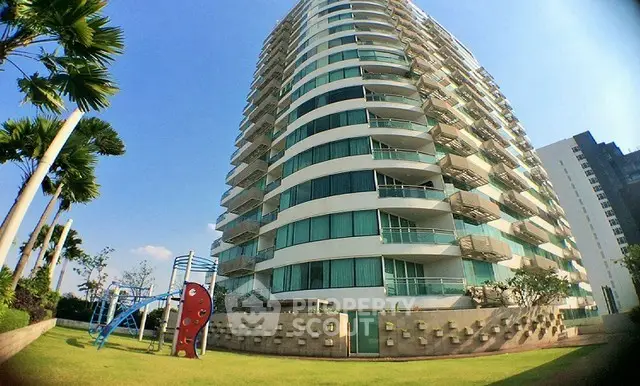 Modern high-rise building with lush garden and playground, perfect for family living.