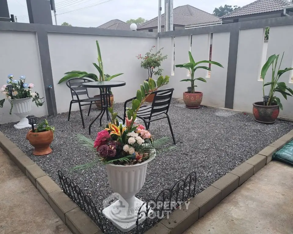 Charming garden patio with stylish outdoor seating and lush potted plants, perfect for relaxation.
