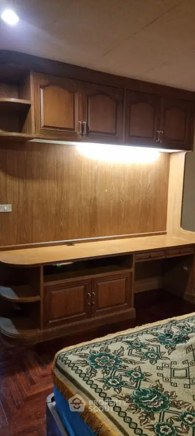 Cozy bedroom with built-in wooden desk and cabinets, perfect for study or work.