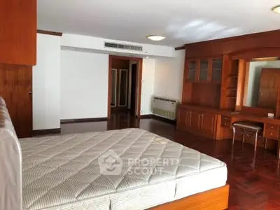 Spacious bedroom with wooden flooring and built-in wardrobe in a modern apartment.