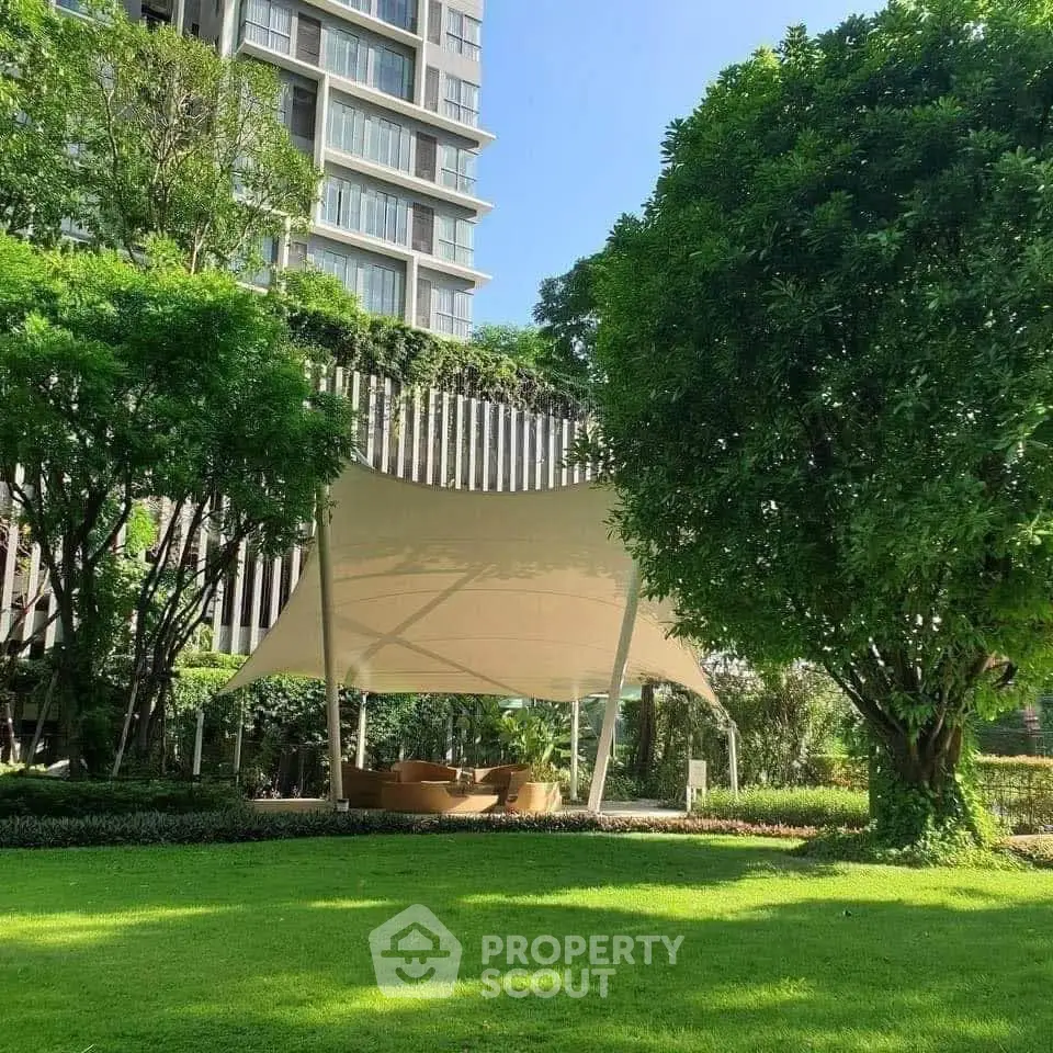 Luxurious garden area with modern canopy and lush greenery in upscale residential complex.