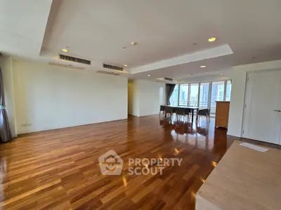 Spacious open-plan living room with hardwood floors and city view, perfect for modern living.
