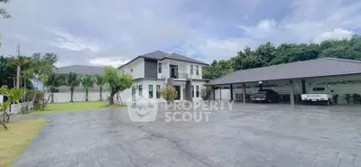 Spacious modern home with large driveway and carport, surrounded by lush greenery.
