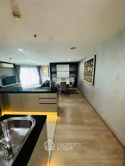Modern open-plan living room with sleek kitchen and stylish dining area, featuring contemporary decor and ample natural light.
