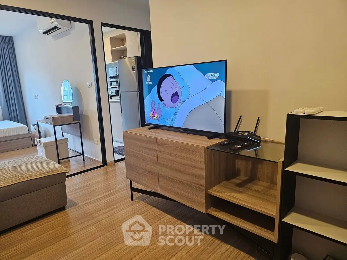 Modern living room with wooden flooring, TV, and stylish furniture in a cozy apartment setting.