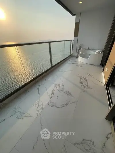 Luxurious balcony with stunning ocean view and elegant marble flooring at sunset.