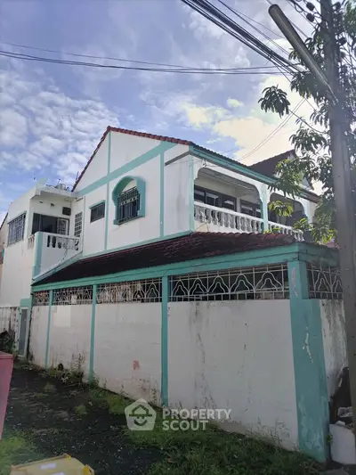 Charming two-story house with unique architectural details and spacious balcony, perfect for family living.