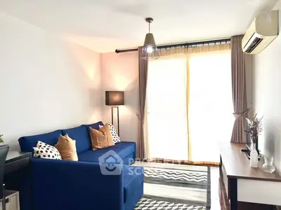 Bright living room with blue sofa, modern decor, and large window with curtains.