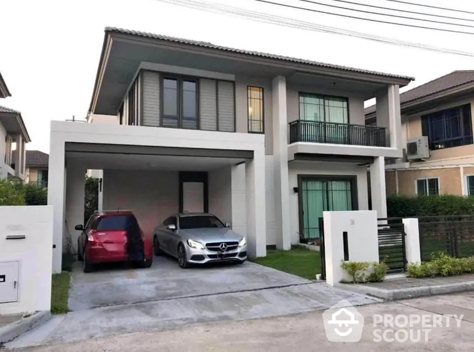 Modern two-story house with driveway and parked cars in suburban neighborhood.