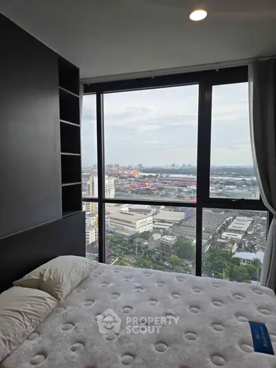 Modern bedroom with panoramic city view from floor-to-ceiling windows in high-rise apartment.