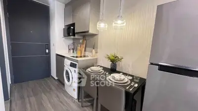 Modern compact kitchen with dining area and washing machine in stylish apartment