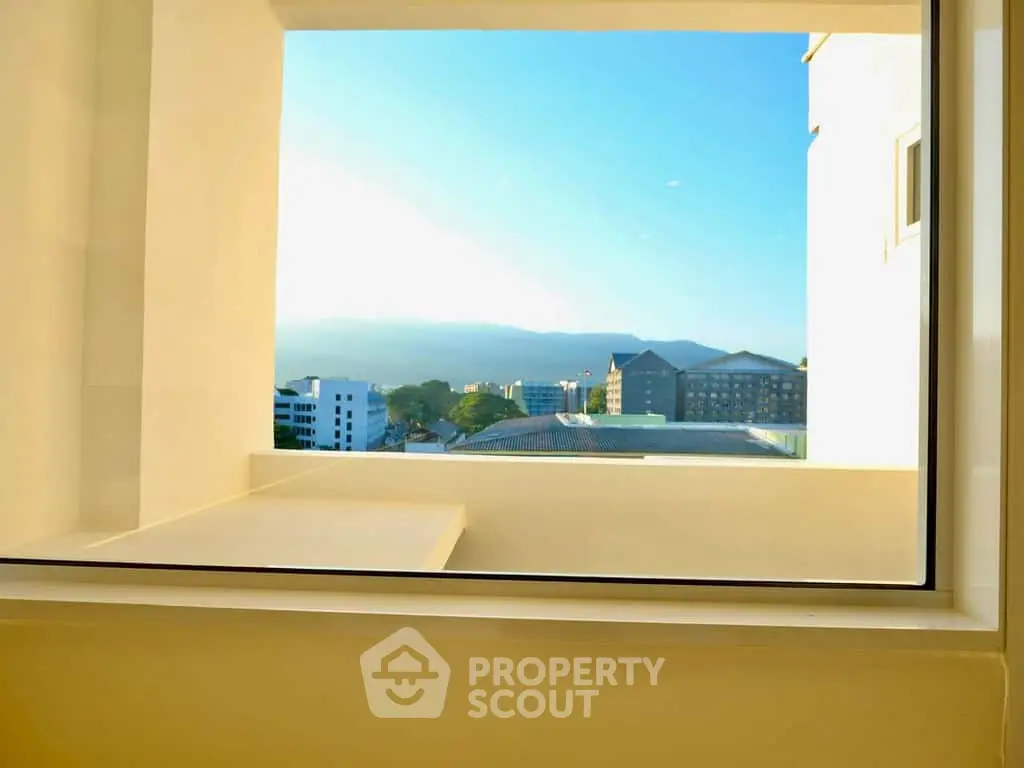 Stunning view from a modern apartment window overlooking cityscape and mountains.
