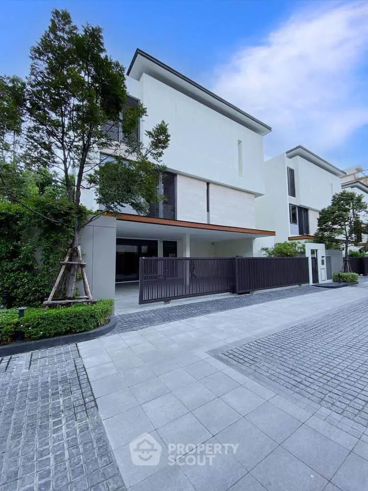Modern luxury townhouse with sleek design and lush greenery in an upscale neighborhood.