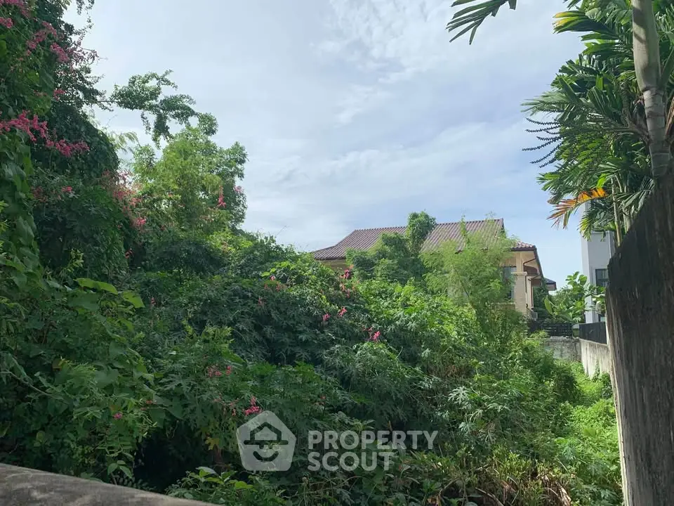 Lush greenery surrounds a charming house with a tiled roof, offering a serene and private retreat.