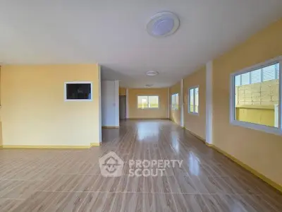 Spacious empty room with large windows and wooden flooring, perfect for customization.