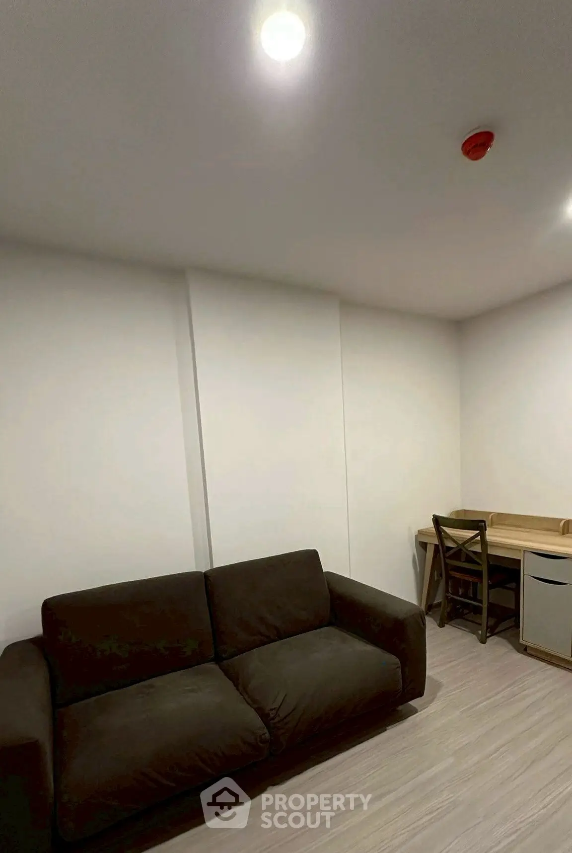 Cozy living room with dark sofa and wooden desk, ideal for small apartments.