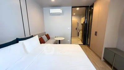 Modern bedroom with cozy bed and sleek kitchen view in stylish apartment