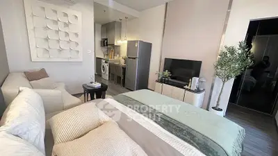 Modern studio apartment with cozy bed, stylish decor, and compact kitchen.