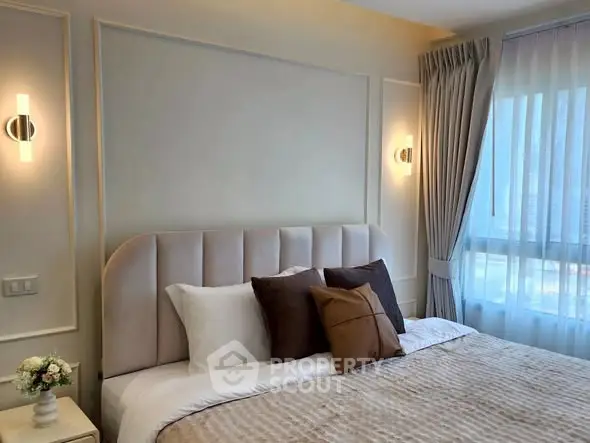 Elegant bedroom with plush bedding and soft lighting, featuring a large window with sheer curtains.