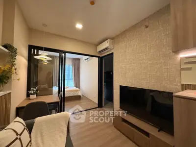 Modern living room with open layout leading to cozy bedroom, featuring stylish decor and natural lighting.