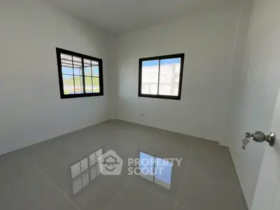 Spacious empty room with tiled floor and large windows, perfect for customization.