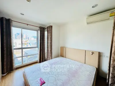 Bright bedroom with large window and city view, featuring a comfortable bed and air conditioning.