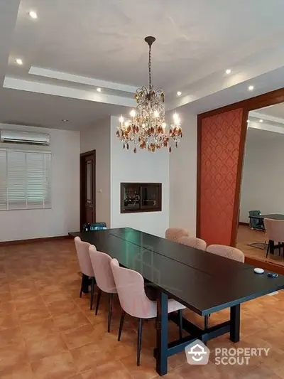 Elegant dining area with a luxurious chandelier, terracotta tiled flooring, and modern furniture, perfect for sophisticated entertaining.