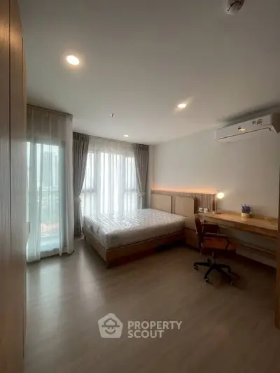Spacious bedroom with modern furnishings and large windows for natural light.