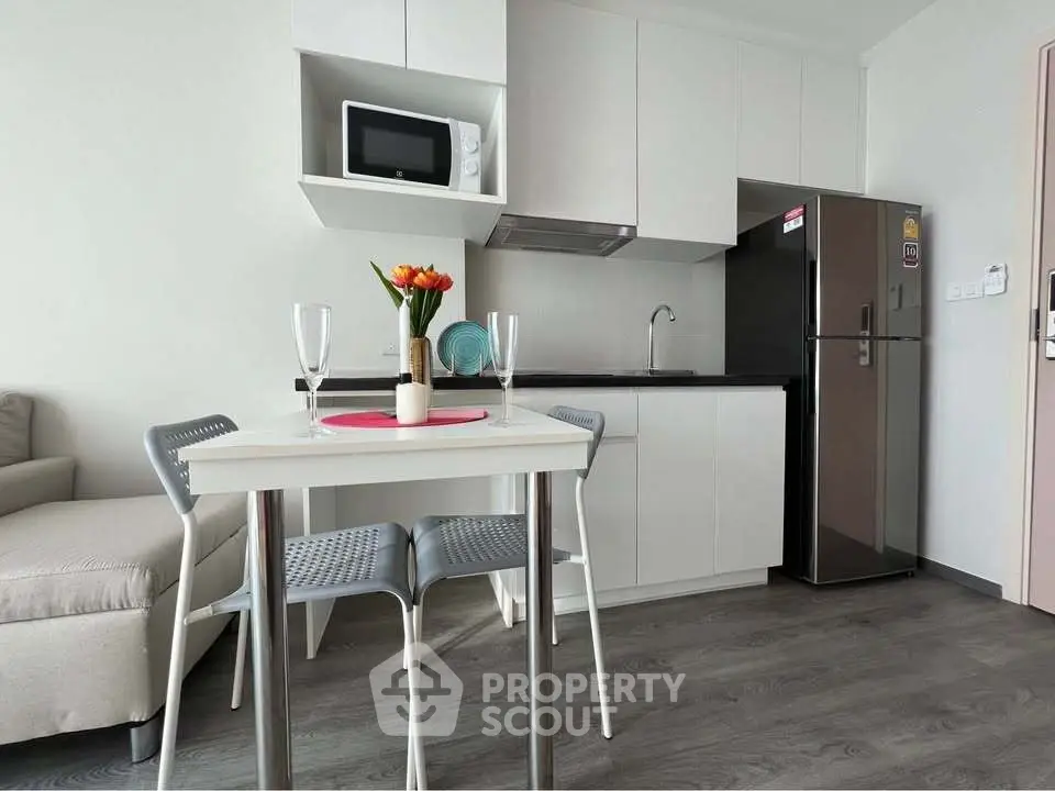 Modern kitchen with sleek appliances and cozy dining area in stylish apartment.