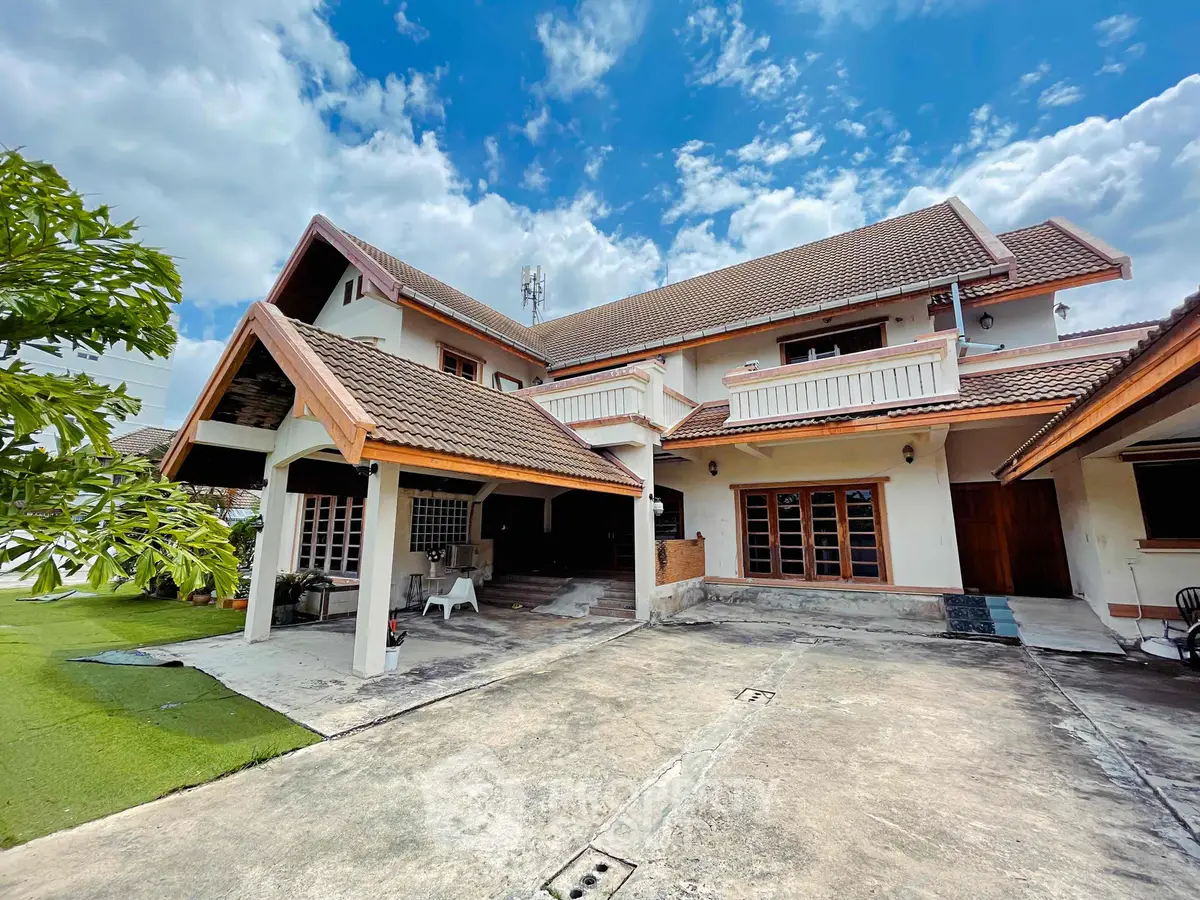 Stunning two-story house with spacious driveway and lush greenery under a vibrant blue sky.