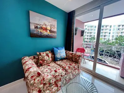 Charming living room with floral sofa and balcony view in modern apartment.