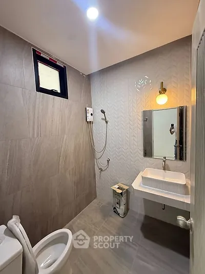 Modern bathroom with sleek design, featuring a wall-mounted sink, toilet, and shower area.