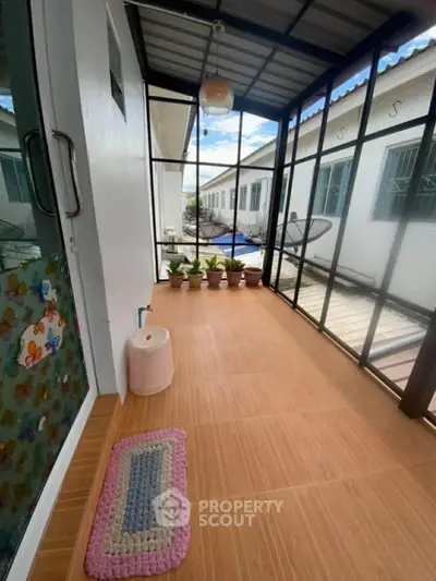 Charming enclosed balcony with tiled flooring and potted plants, perfect for relaxation.