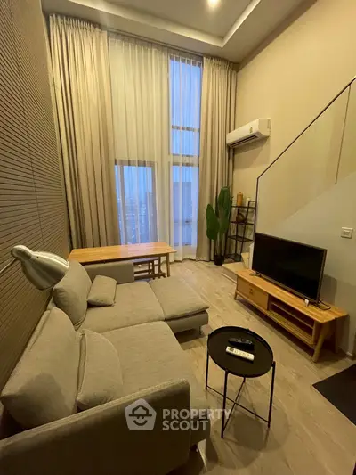 Modern living room with high ceiling, large windows, and stylish furniture