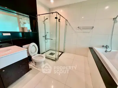 Modern bathroom with glass shower, bathtub, and sleek fixtures in a contemporary home.