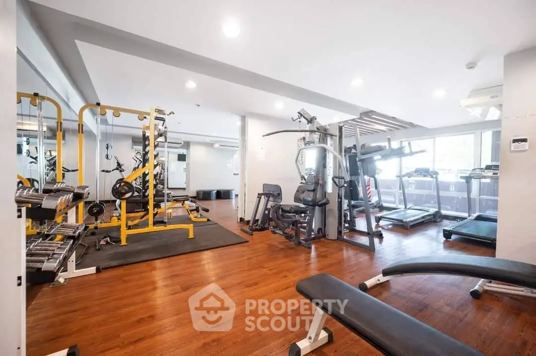 Spacious gym with modern equipment and wooden flooring in a residential building.