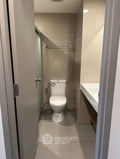 Modern bathroom with sleek design and neutral tones, featuring a toilet and glass shower enclosure.