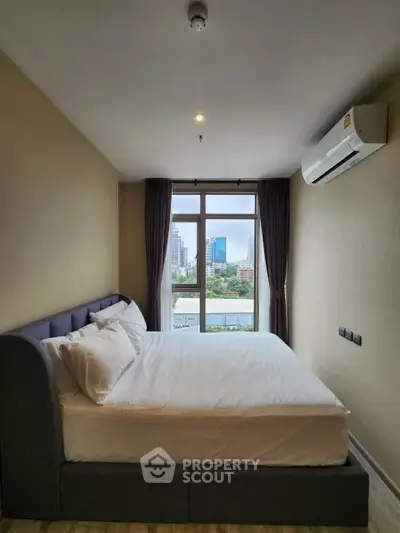 Modern bedroom with city view, featuring a comfortable bed and air conditioning in a stylish apartment.