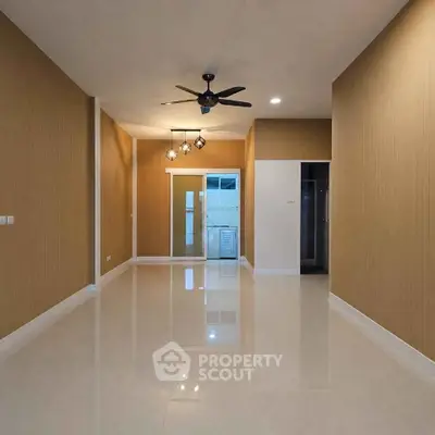 Spacious modern living room with ceiling fan and sleek lighting, perfect for comfortable living.