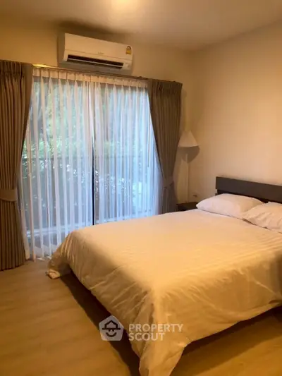 Cozy bedroom with large window and air conditioning, perfect for relaxation.