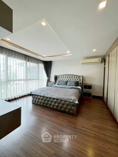Spacious modern bedroom with large windows and elegant furnishings.