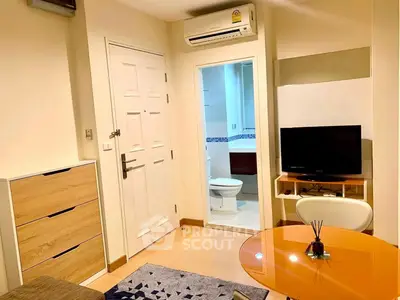 Cozy living room with modern furniture and view into a compact bathroom, featuring a TV and air conditioning.