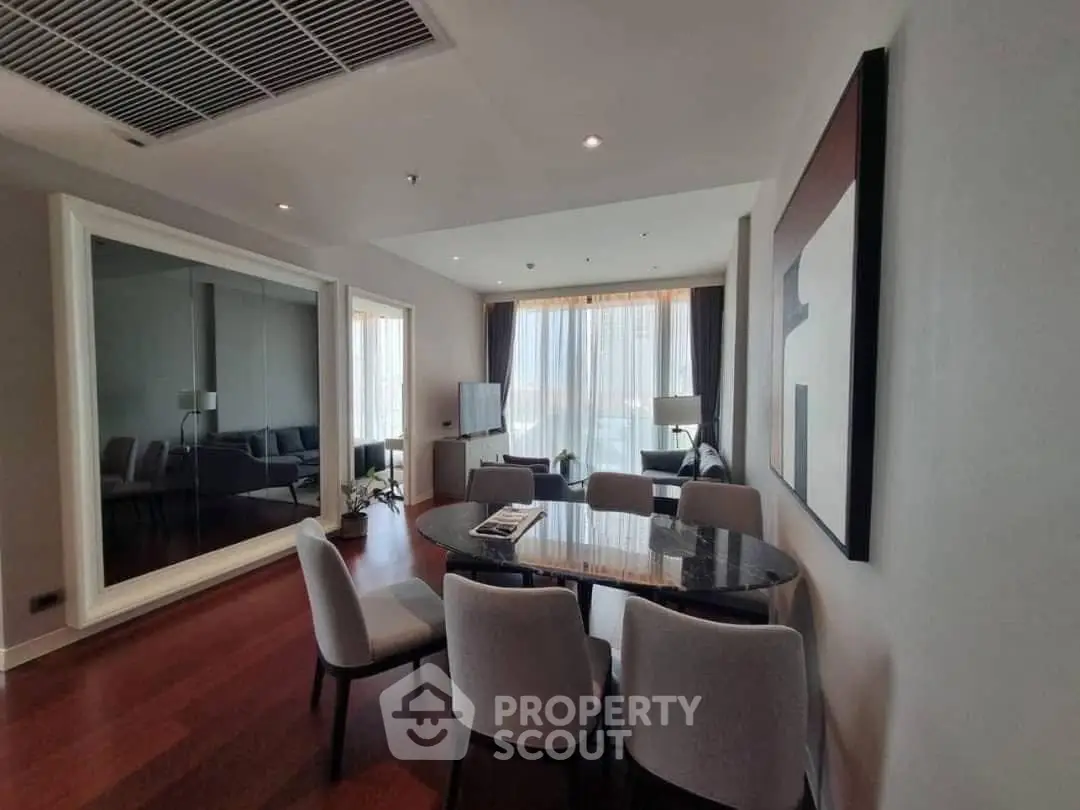 Elegant living room with modern dining area and large mirror, featuring stylish decor and natural light.