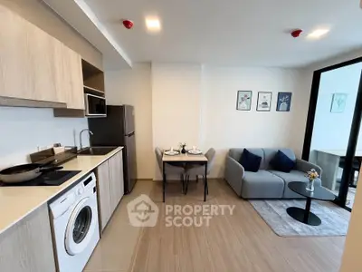 Modern open-plan living room with kitchen, featuring sleek appliances and cozy dining area.