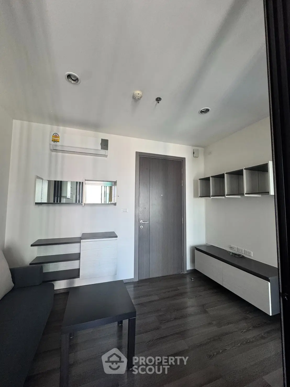 Modern living room with sleek furniture and dark wood flooring in a contemporary apartment.