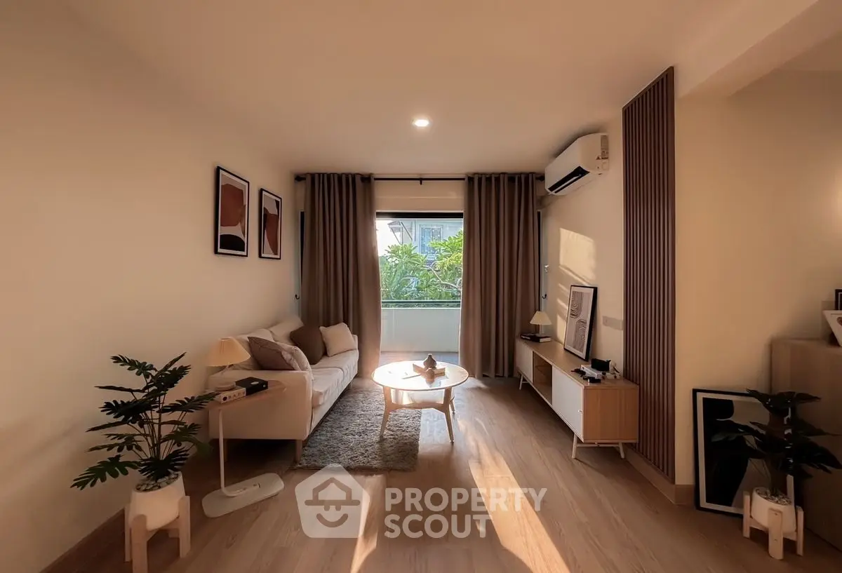 Charming living room with cozy decor and natural light, featuring modern furniture and lush greenery view.