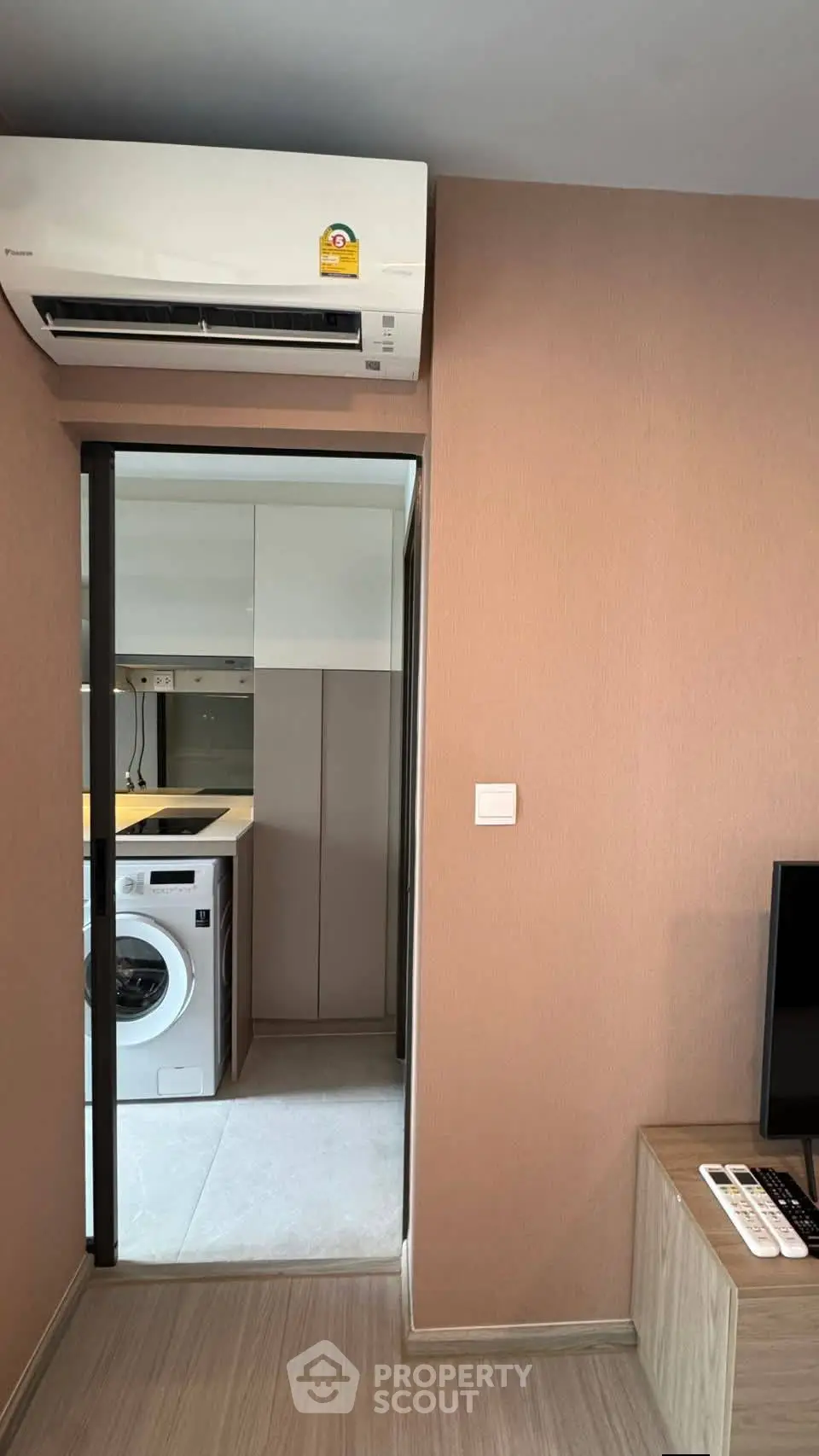 Modern apartment interior with air conditioning and washing machine in a compact laundry area.