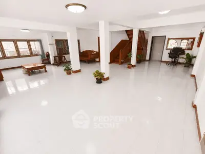Spacious open-plan living area with elegant wooden staircase and abundant natural light.