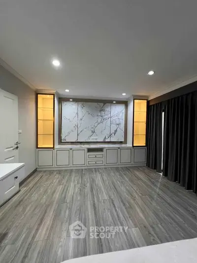 Spacious modern living room with elegant wood flooring and built-in shelving, perfect for stylish living.