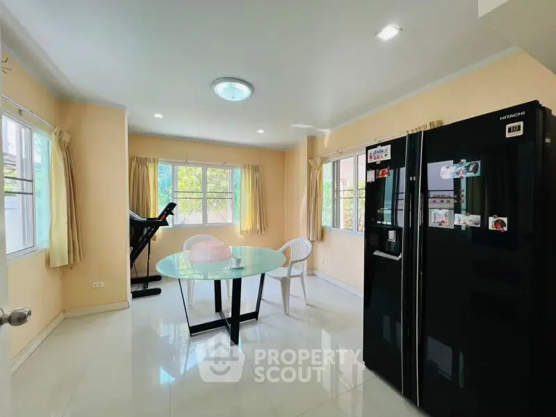 Bright kitchen with modern black fridge and round glass table